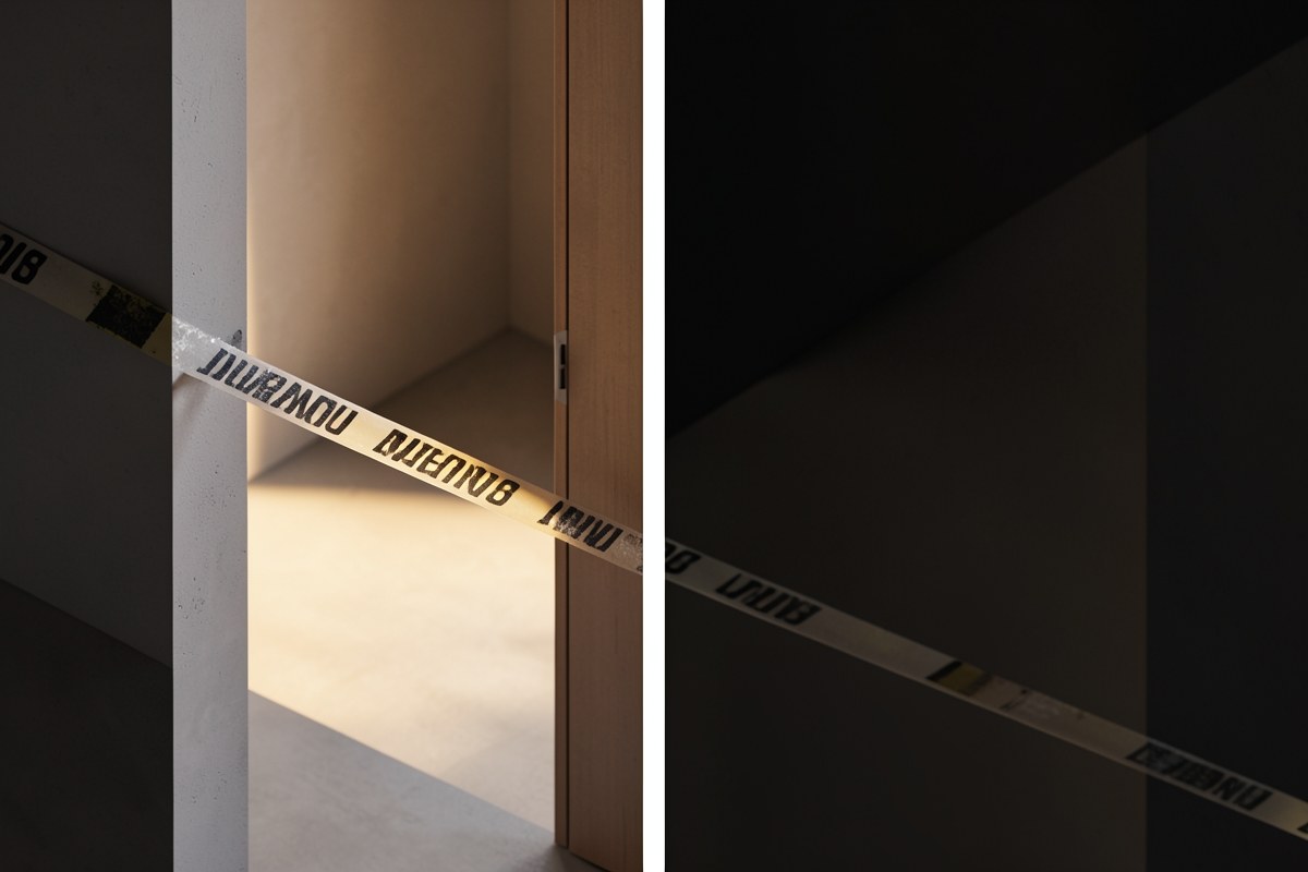 A yellow warning tape on the floor in front of a simple doorway, suggesting an important warning.